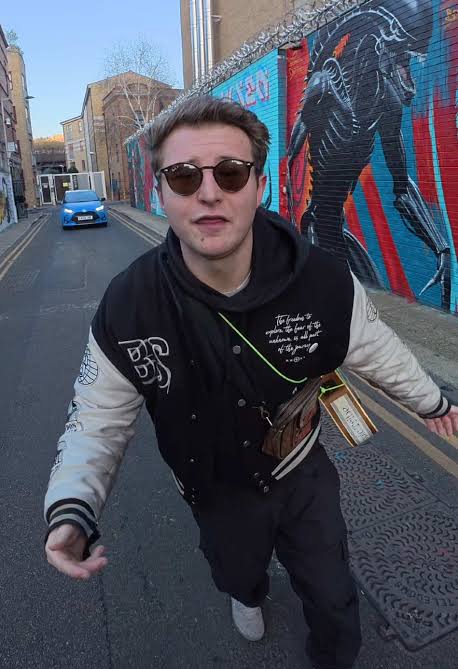 Liam C wearing a varsity jacket on a graffiti-covered street